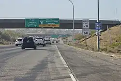 Looking from the shoulder of a freeway at an overpass with signs reading "To Interstate 82 - Yakima, Pendleton" and "West SR 240 - Wellsian Way, Vantage" with route markers for Interstate 182 and U.S. Route 12 off to the side.