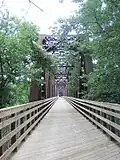 Looking west along the length of the bridge from the eastern end, you can see the newly constructed wooden bridge deck and the safety railings.