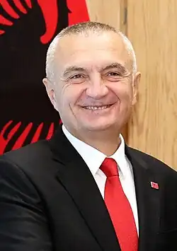 Head shot of Meta smiling with an Albanian flag in the background