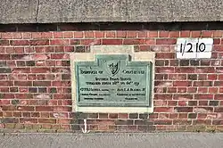 Green plaque mounted on a brick wall