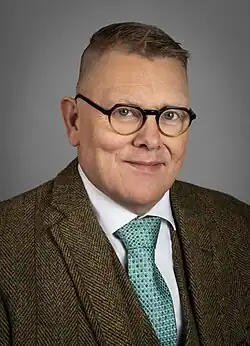 Headshot of Jón Gnarr, a middle-aged white blond man with wearing a morning suit.