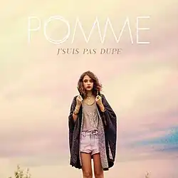 Photo of a brunette woman standing with a long shawl against a cloudy sky. The words "Pomme" are placed above her while the words "J'suis pas dupe" are placed beneath the former, stylized in all capital letters.