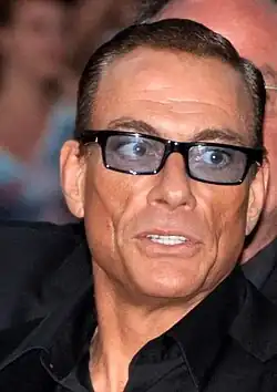 Middle-aged, dark-haired man in a black suit and blue tinted glasses