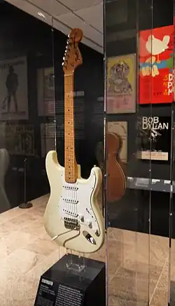 A color photograph of a white Fender Stratocaster guitar