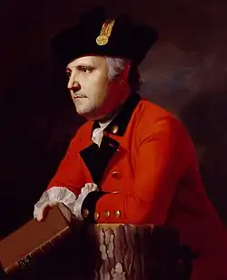 Painting of a determined-looking man in a red military coat with black lapels and a black hat