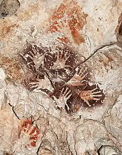 Le « Bouquet de mains », une manifestation remarquable de l’art rupestre de Bornéo, met en scène six mains dans une ronde graphique éternelle. A noter des mains de couleur rouge orangé plus anciennes recouvertes par le motif.