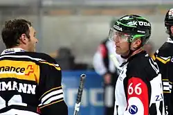 Two men - one a player, the other a referee - chatting on ice