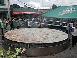 A photograph of people cooking a 5.5 meter-wide pupusa