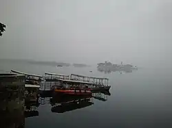 Boats floating in Lake Pichola, and Jag Mandir in background, in a typical cloudy day in rainy season.