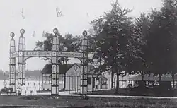 Historic black and white photograph showing Lake Orion resort buildings along the waterfront with boats docked nearby