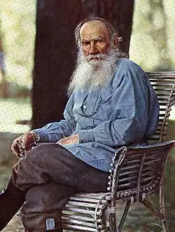 Tolstoy with long white, whispy beard wearing a blue button-down shirt