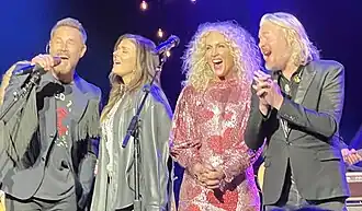 The four members of Little Big Town, holding microphones and singing on a stage.