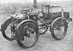 A sepia monotone image of motorized four wheeled vehicle built in 1898 by Royal Enfield.