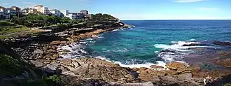Mackenzies Bay, as a rocky inlet, in April 2013. The headland in the background is Mackenzies Point. Both are on the route of the Bondi to Coogee urban coastal walk,[17] which is visible in the upper-left.
