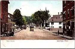 A postcard view of a streetcar in a small downtown