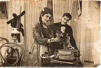 Black and white photo of a woman receiving flowers, a man at her side smiles.