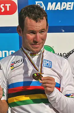 A man on a podium holding a medal around his neck