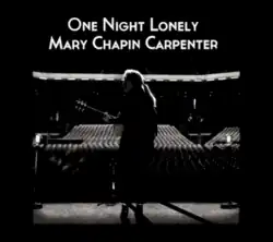 A black-and-white photo shot behind Carpenter onstage holding her guitar in front of an empty auditorium