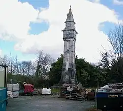 A dilapidated Victorian campanile-style obelisk beside an industrial yard