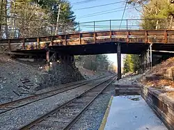 A wooden bridge with one stone abutment over a railway line