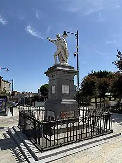 Photograph of a statue depicting Fr Michael Murphy atop a plinth, with his arm raised. The plinth bears the year "1798", and a portrait of Wolfe Tone.
