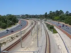 A railway line in a freeway median strip viewed from a footbridge