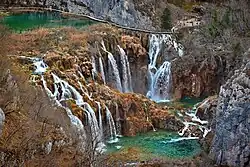 A series of waterfalls cascading over vegetation-covered slopes