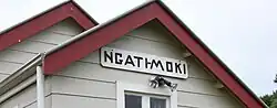 cropped image shows red roof line, weather board building and hand painted sign saying Ngati Moki