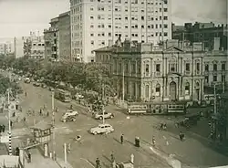 Electric trams and motor cars at a crossroads in a densely built up area