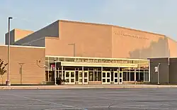 Large mostly windowless brick building with wide row of doors attached to the right of the school