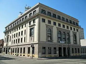 A five-story tan building seen at an angle, with the front entrance to the right.