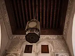 Wooden roof and stucco decoration over the street in front of the madrasa's entrance