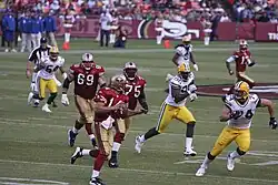 Green Bay Packers players chasing San Francisco 49ers players on a field