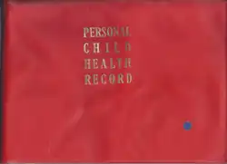 The front cover of a book, with a solid red background and the words 'PERSONAL CHILD HEALTH RECORD' in gold serif justified typeface on alternating lines. A small blue circular sticker is present in the bottom right.