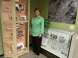 Dorothy Gunderson, of the Sunnyslope Historical Society and Museum, poses in front of the John C. Lincoln display in the historical building which once housed the Peoples Drug Store.