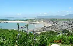 Panorama of a town at a sandy beach, surrounded by green vegetation