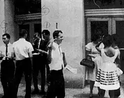 Oswald is pictured passing out pamphlets on a street in New Orleans. Other men, possibly Cuban, are also passing out pamphlets behind him