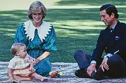 A young William, sitting with his parents on a mat, playing with a toy