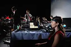 Electroencephalophone as part of live performance. Using brainwaves the quintist directly interfaces to a music synthesizer, playing along with the other band members. A closed-loop system functions analogously with a regenerative receiver.