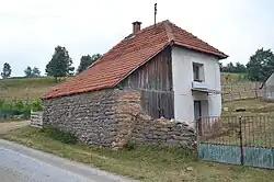 A small building with a red roof and walls of wood and stone