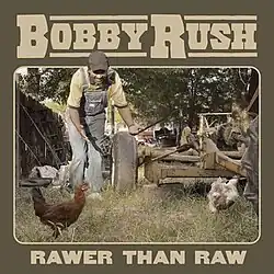 Bobby Rush, wearing overalls in a farmyard