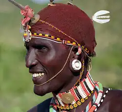 A close up profile of a girl wearing a beaded headdress and necklace with her neck painted with red ochre.