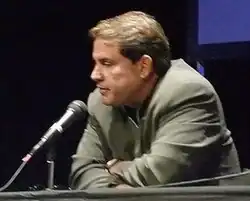 Rick Sanchez sitting in front of a microphone, slightly hunched over.