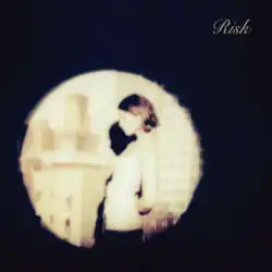 A young brunette woman highlighted by a spotlight. The title, "Risk" is written in the top right corner