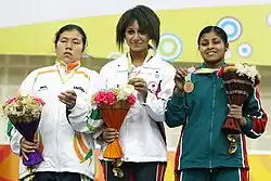 Three women holding medals and bunches of flowers.