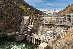 Front view of a concrete dam, with a river flowing off downstream to the left.