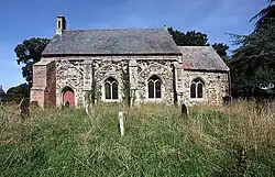 A simple stone church, consisting of a nave and a smaller chancel, seen from the south