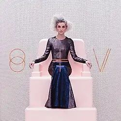 Image of St. Vincent seated on a plastic pink throne with a glittery purple dress and curly silver hair