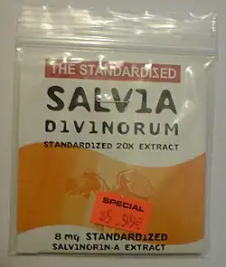 A rectangular plastic re-sealable zipper storage bag that appears to be approximately 10 by 15 centimeters. The bag has a white label and a large wavy orange stripe. The top of the label reads: "THE STANDARDIZED SALVIA DIVINORUM" in large letters and "STANDARDIZED 20X EXTRACT" in smaller letters immediately below. The bottom of the label reads "8 mg STANDARDIZED SALVINORIN-A EXTRACT" in small letters. Affixed to the bag is an orange price tag reading "SPECIAL $5.99."