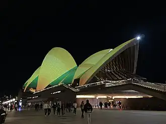 The sails of the Sydney Opera House lit up in green and gold